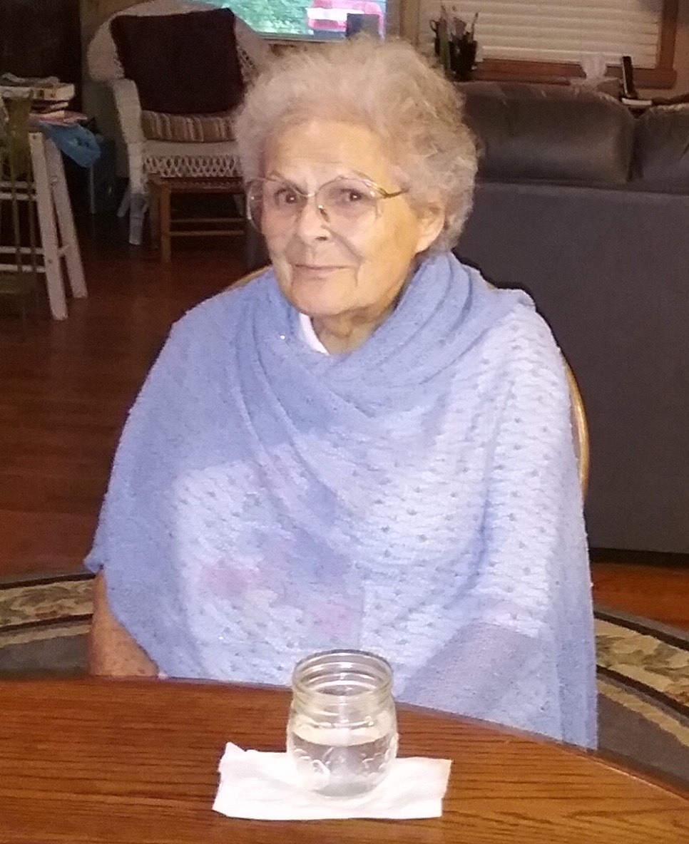 Elderly Woman Seated at a Table Wrapped in a Shawl Indoors