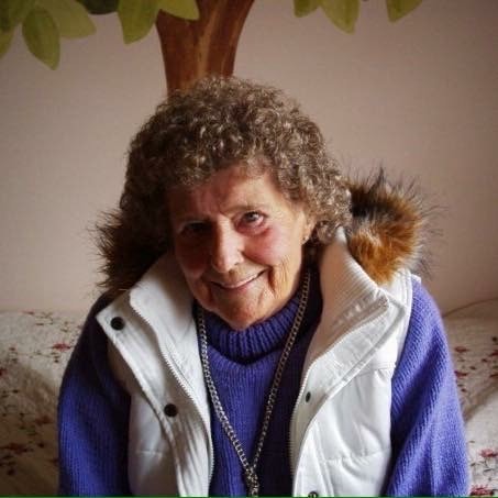 Elderly Woman Smiling Warmly While Seated Indoors